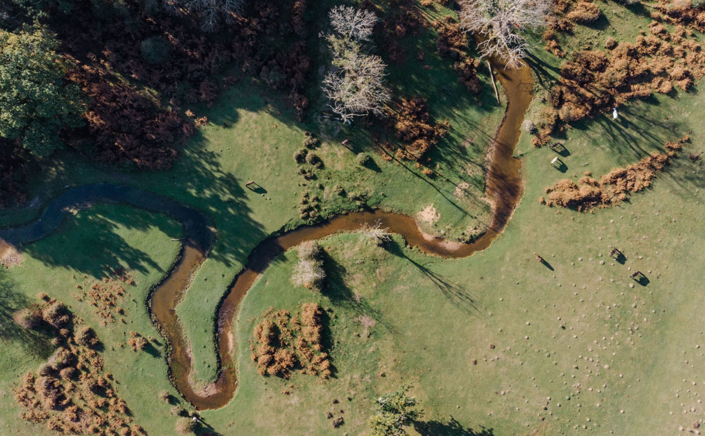 Arial photograph of a river winding through a landscape of grass and trees.