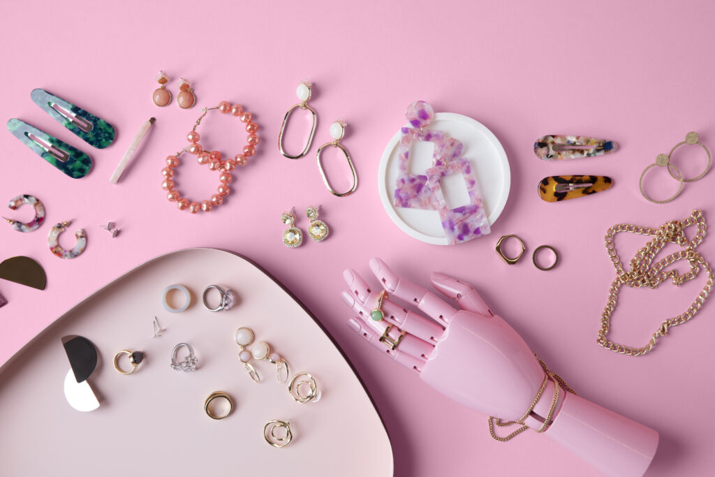 Photograph of jewellery and hair accessories against a pink background.